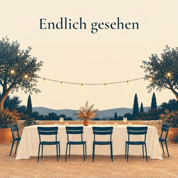 Gemaltes Bild mit dem Text Endlich gesehen: eine lange weiße Hochzeitstafel unter Lichterketten zwischen Olivenbäumen, davor blaue Stühle.
